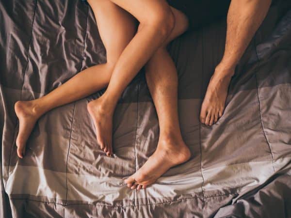 casal na cama com as pernas entrelaçadas